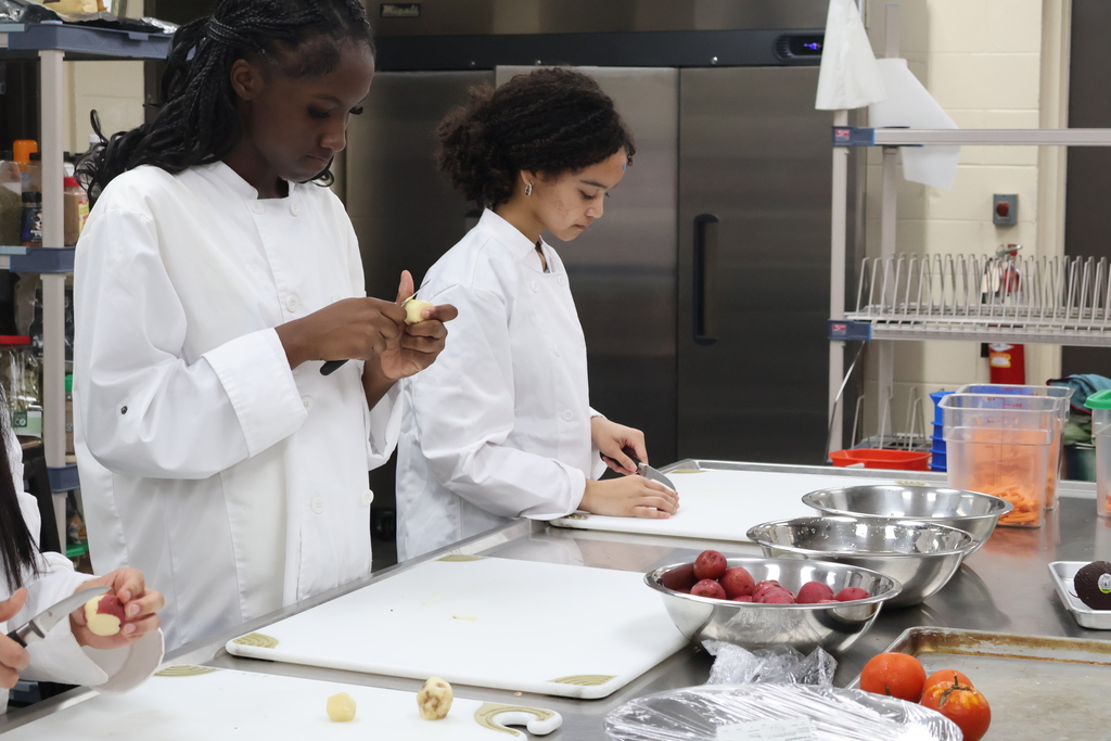 Two students are cutting up potatoes. 