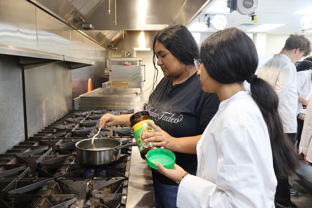 Two students are adding spices to their pot of rice. 