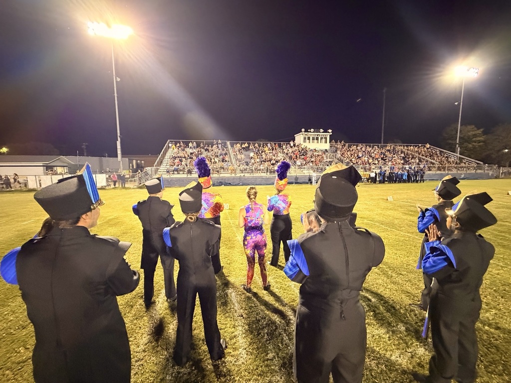 The band students are on the football field during their performance. 