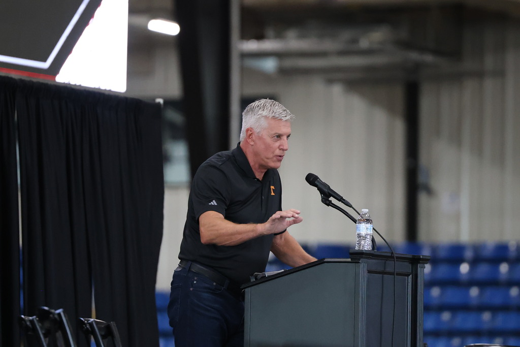 A man is standing at a podium on the stage inside Cooper Steel Arena and is speaking to the crowd. 