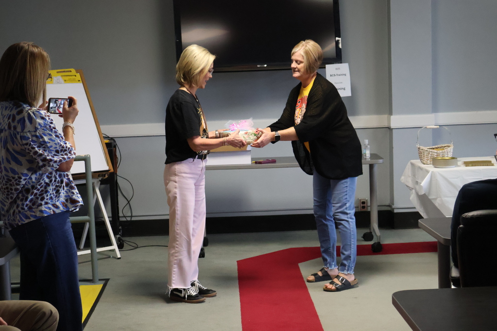 A woman is handing another woman a gift. 