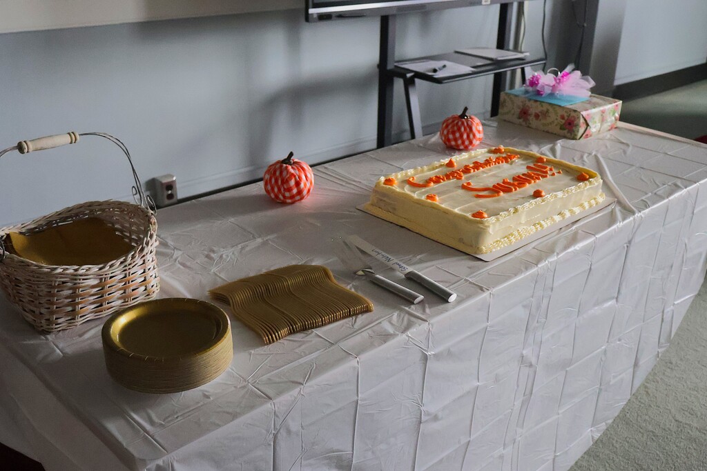 A white and orange cake are on a table that is decorated. 