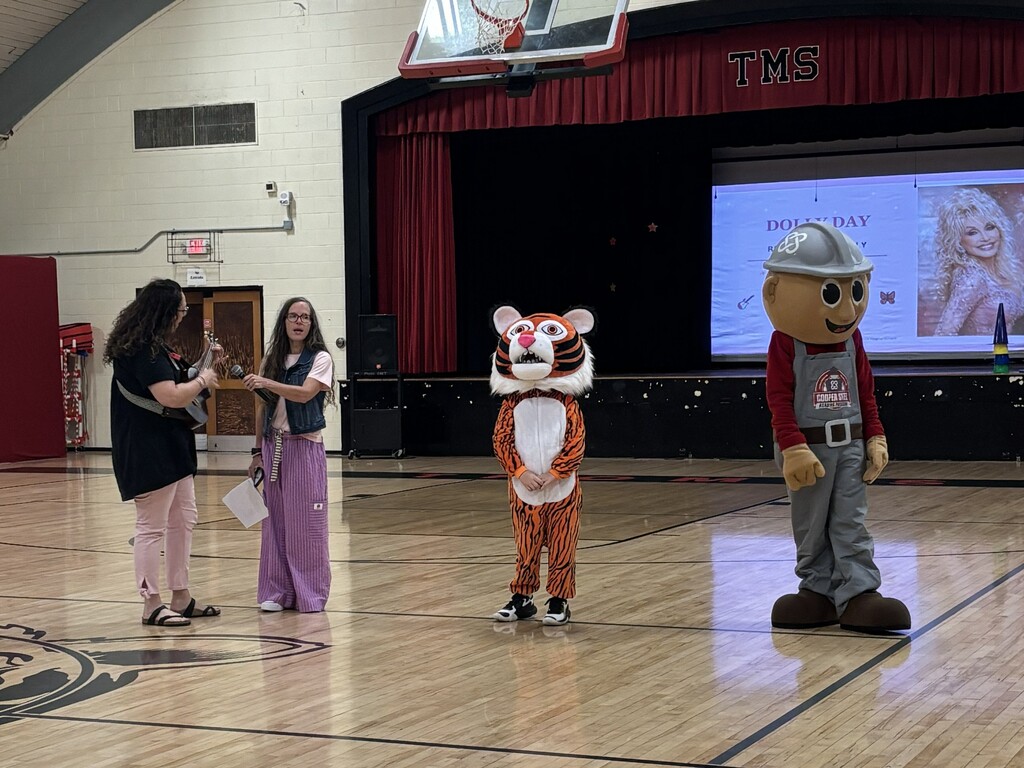 Teachers with mascots and Dolly Parton's picture in the background