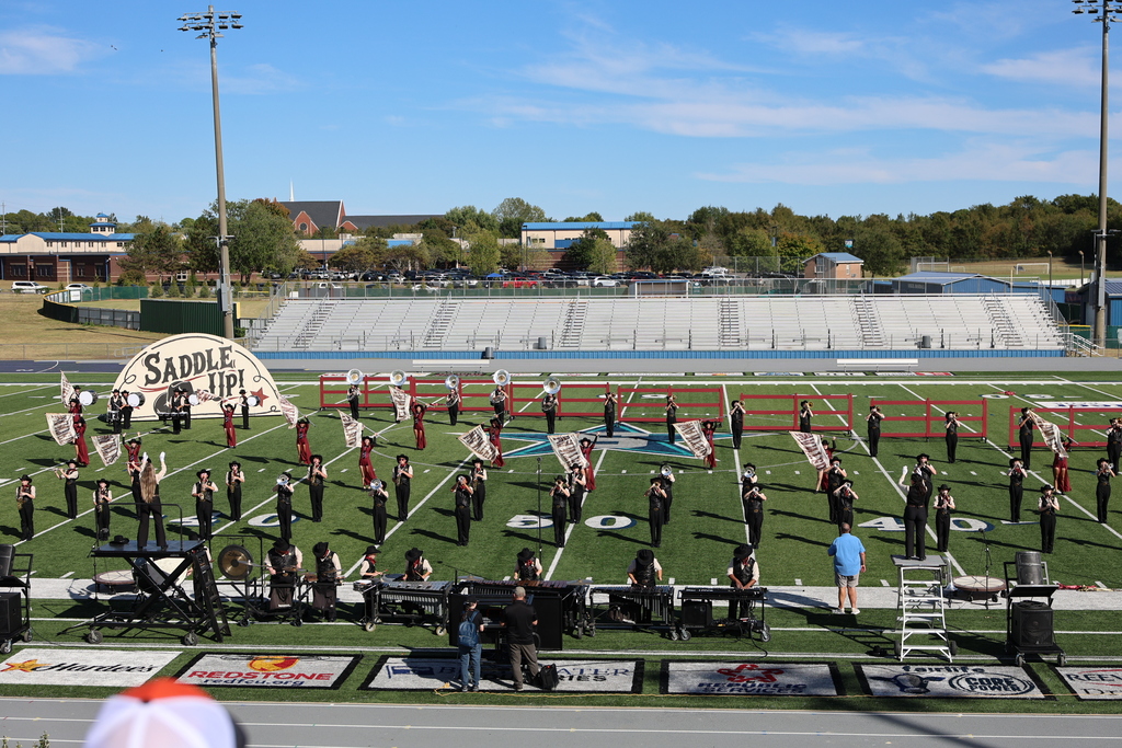 The marching band are on the football field during their performance. 