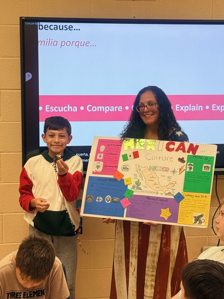 A teacher is holding a homemade poster up about Mexico while a student is standing beside her. 