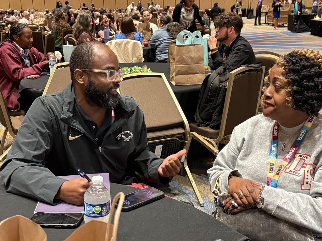 A man and a woman are sitting at a table discussing topics from the conference. 