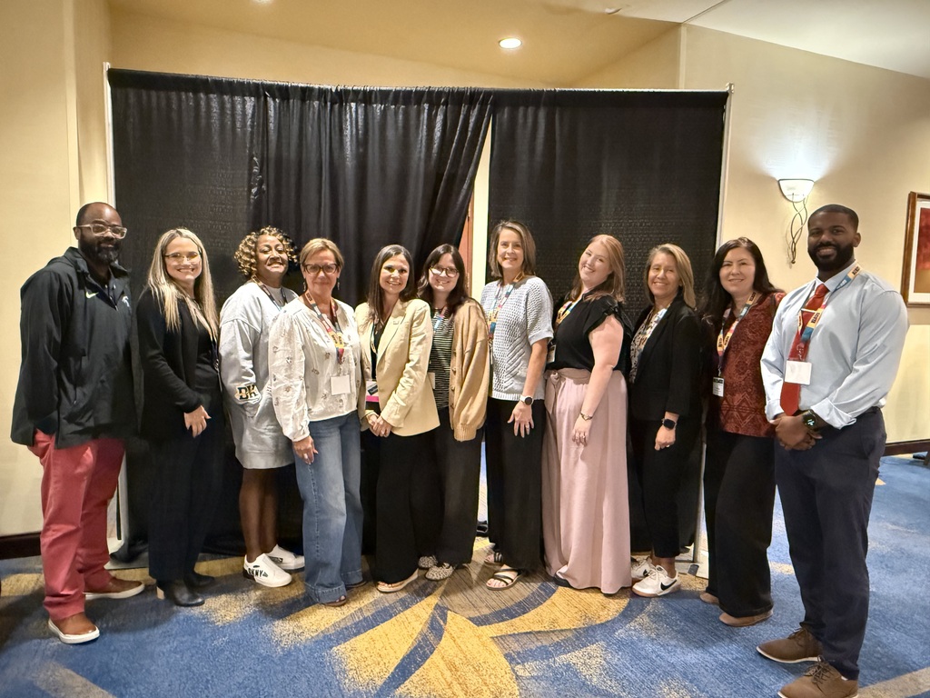 Several people are all posed for a group picture at the SCALI conference in front of a black backdrop. 