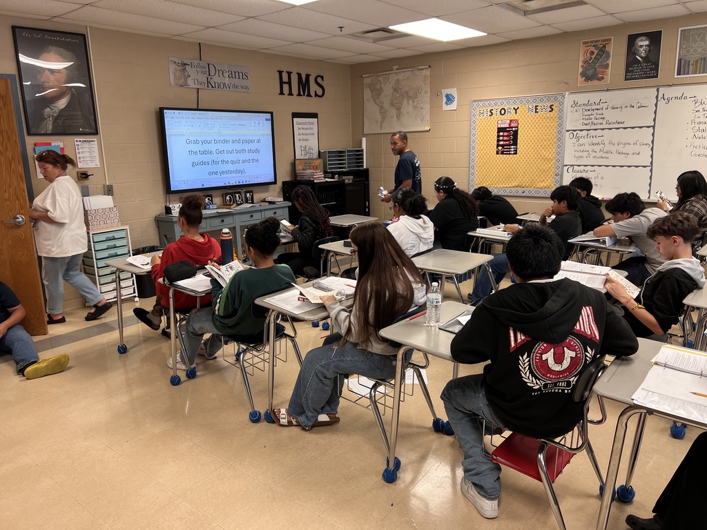 Students are sitting at their desks in the classroom reading books. 