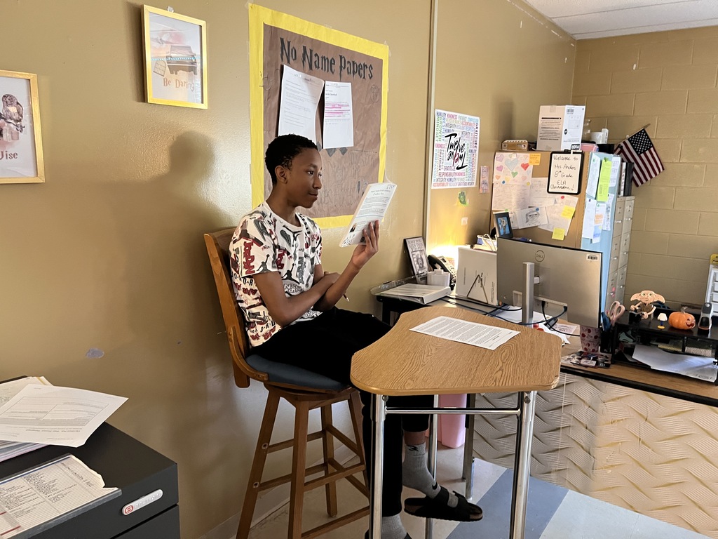 A student is sitting at a table reading a book. 