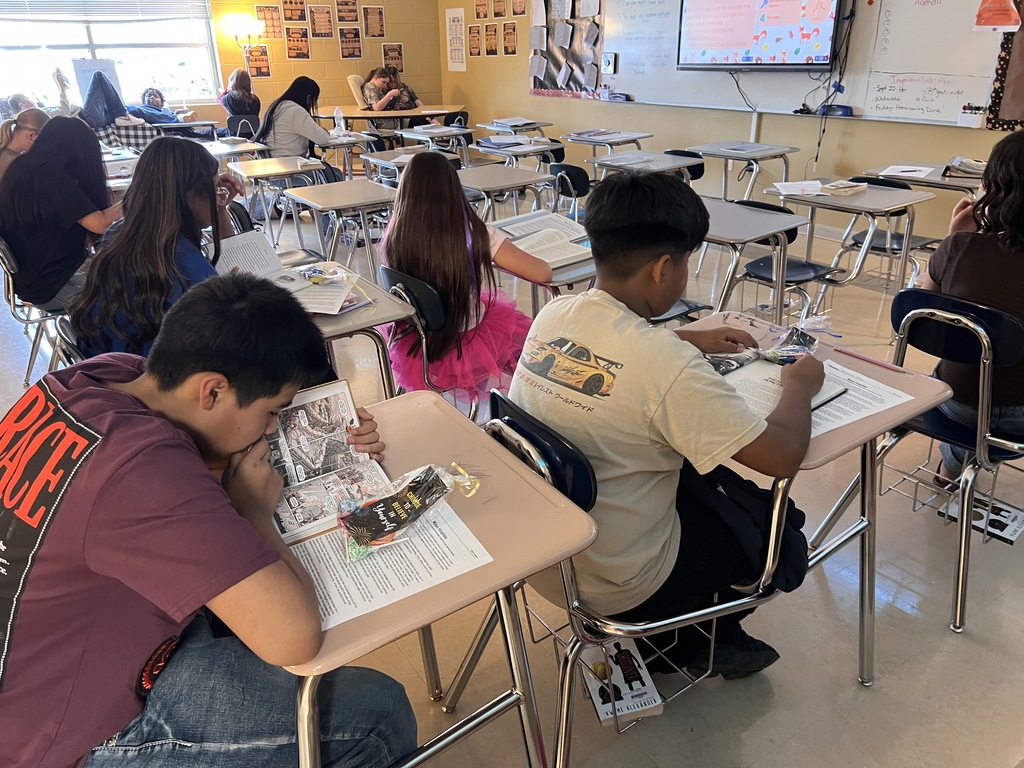 Students are sitting at their desks in the classroom reading books. 