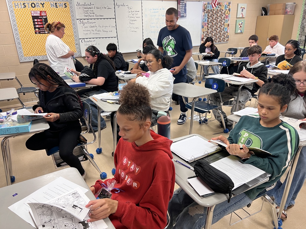 Students are sitting at their desks in the classroom reading books. 