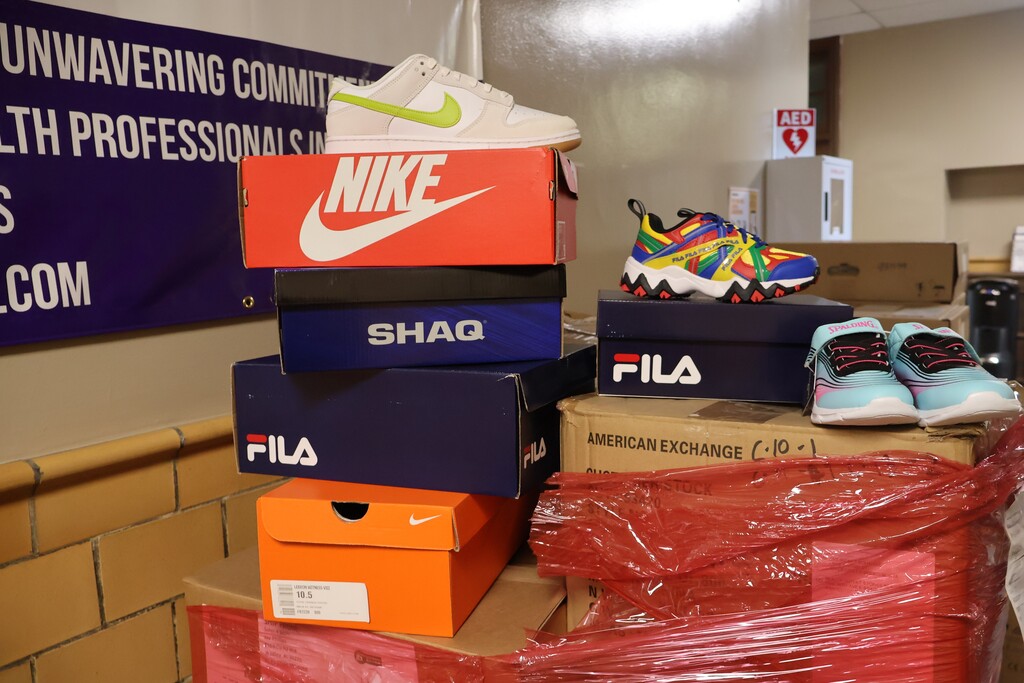 There are boxes of shoes sitting out of the wrapping paper on top of their boxes to show some of what was in the pallet of donated shoes. 