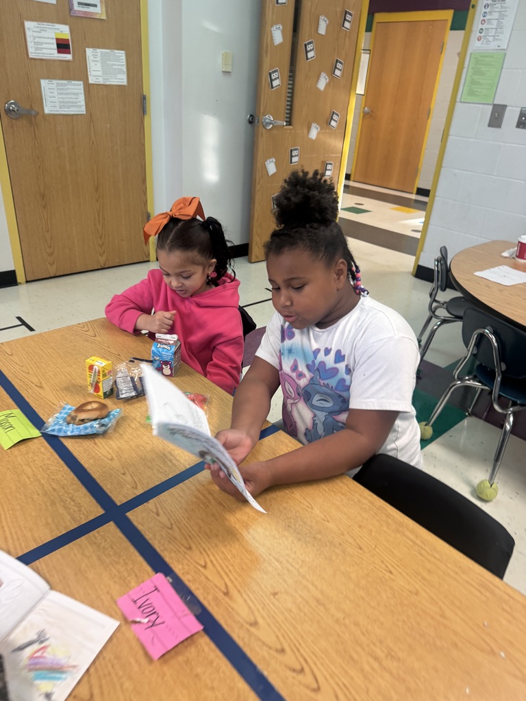 1 student reading to another while the other eats