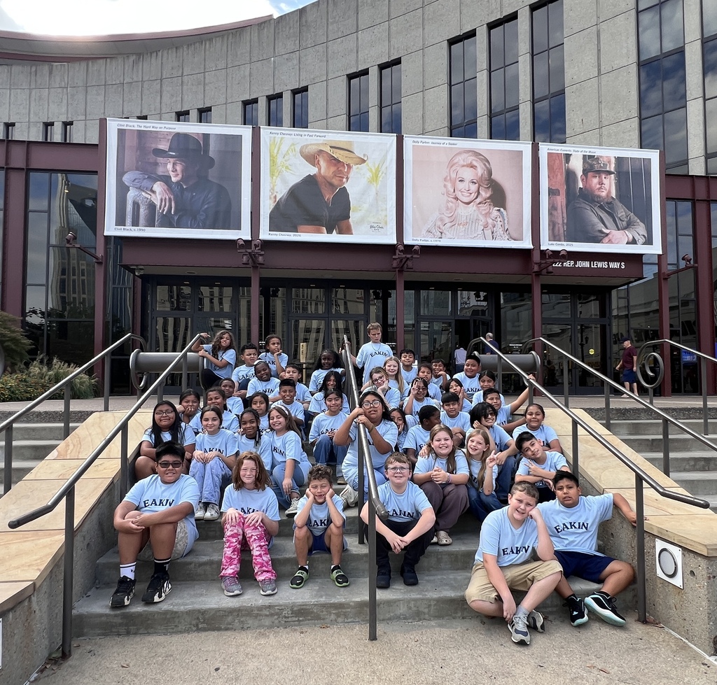There is a large group of students all posed on the stairs for a group picture in front of the country music hall of fame sign.