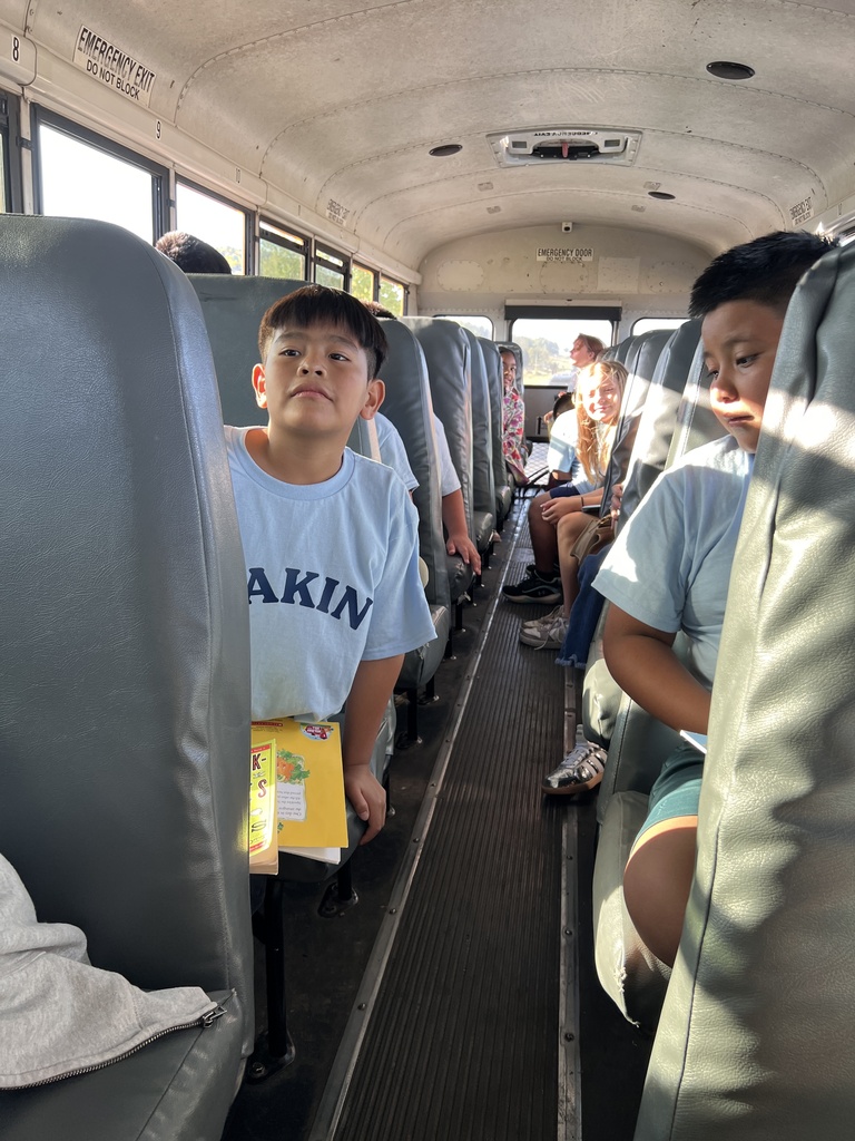 Students are sitting in their bus seats as they are on their field trip. 