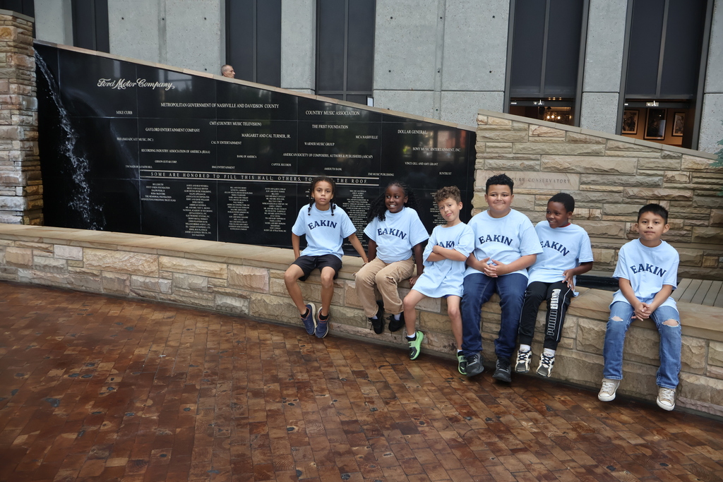 There are six students who are all sitting on a stone wall posed for a picture. 