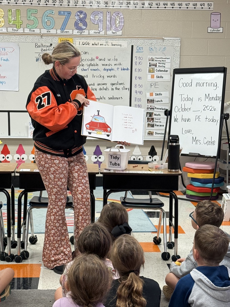 National Honor Society students from Cascade High School reading to first grade students at Cascade Elementary during Reading Buddies Day, sharing books and personal reading journeys in decorated classroom.