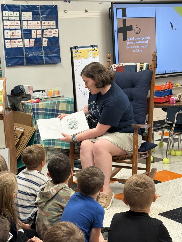 National Honor Society students from Cascade High School reading to first grade students at Cascade Elementary during Reading Buddies Day, sharing books and personal reading journeys in decorated classroom.