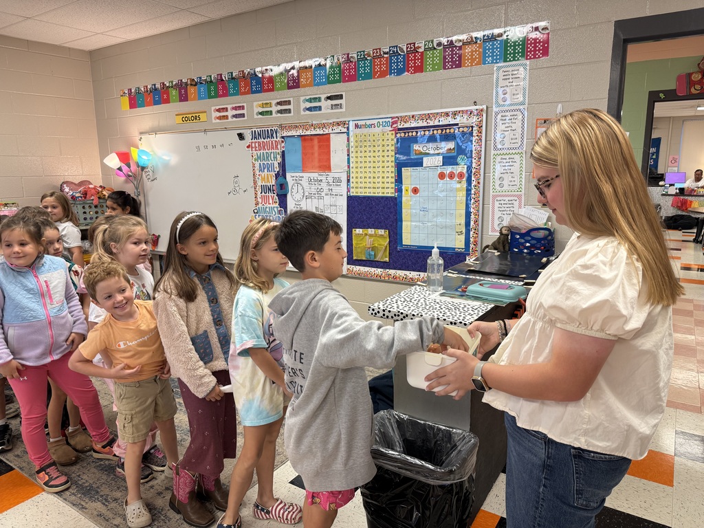 National Honor Society students from Cascade High School reading to first grade students at Cascade Elementary during Reading Buddies Day, sharing books and personal reading journeys in decorated classroom.