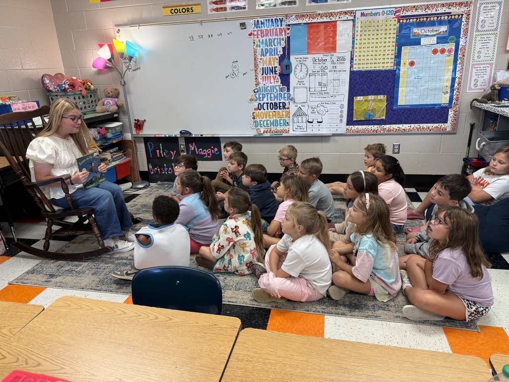 National Honor Society students from Cascade High School reading to first grade students at Cascade Elementary during Reading Buddies Day, sharing books and personal reading journeys in decorated classroom.