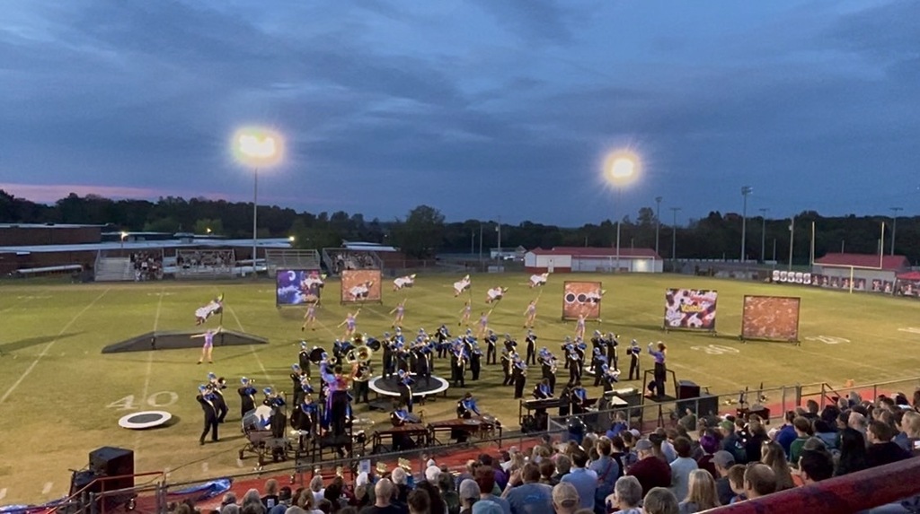 The marching band is on the football field during their performance.