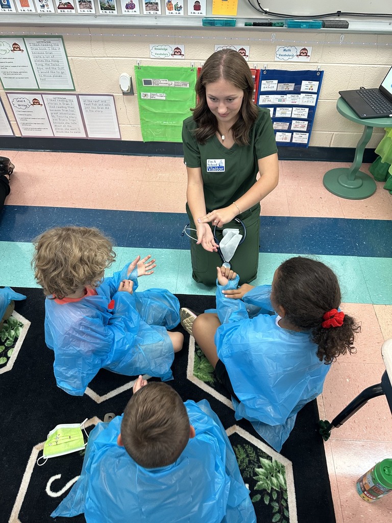A HOSA student is showing younger students how to find their pulse on their arms.