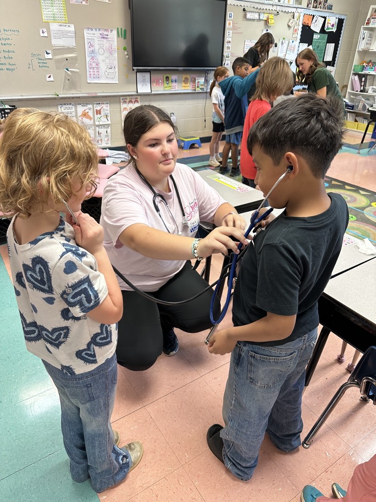 A HOSA student is letting two students use a stethoscope to listen to their heartbeats.