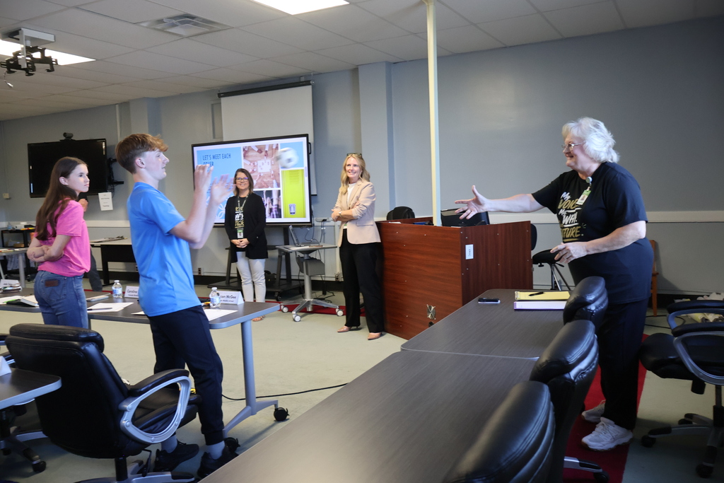 A woman tosses a ball to a student while two adults and another student watch. 