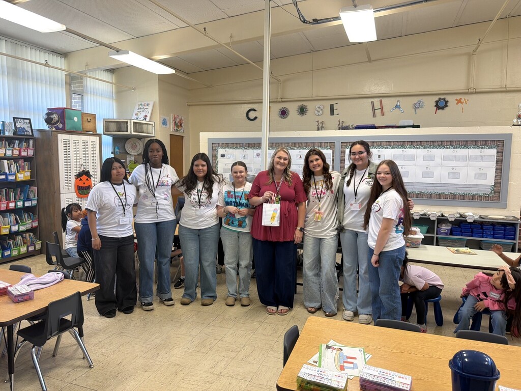 Several high school students are posed for a picture with a teacher.