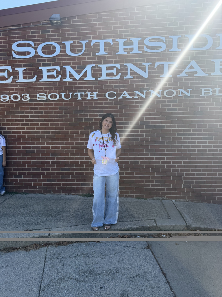 A high school student is posed in front of Southside Elementary School's sign in front of the school.