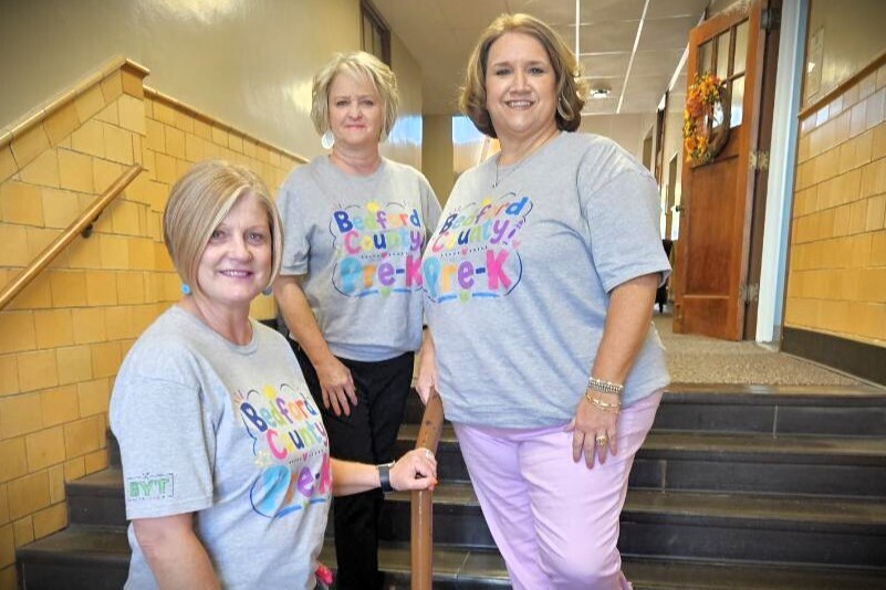 Three women are posed for a picture wearing matching t-shirts.