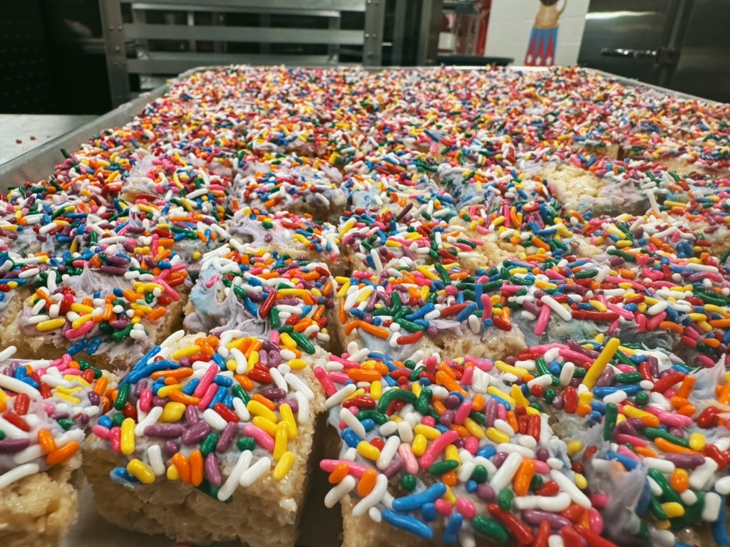 A big cake in a pan is covered in colored sprinkles. 