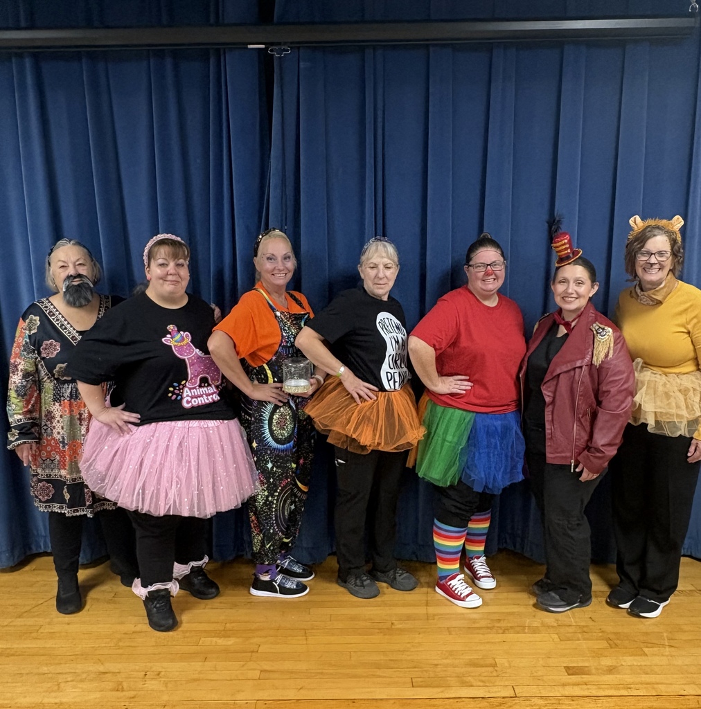 Seven women pose for a group picture and each are dressed in a circus themed costume. 