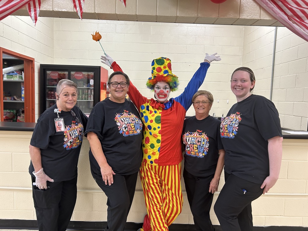 Five women are posed for a group picture in their cafeteria.