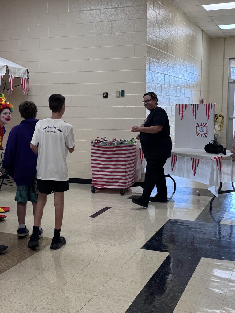 A cafeteria staff member is playing a circus themed game with several students.