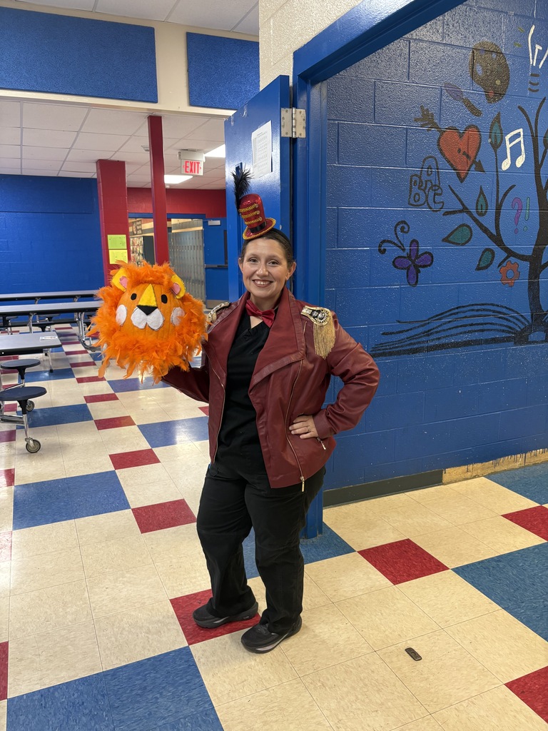 A woman is holding a lion head prop while dressed in circus themed attire. 