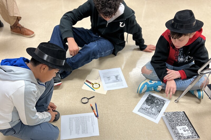 Three students are sitting on the floor discussing the book and their findings.