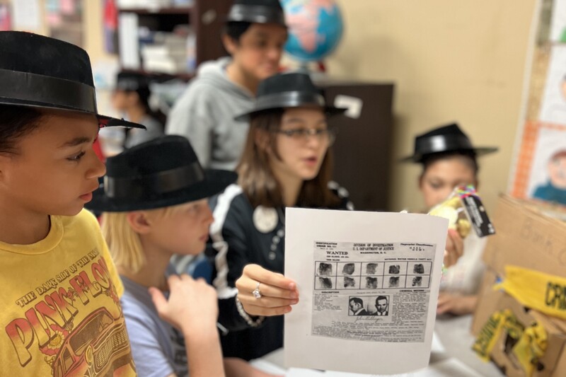Students are sitting at a table discussing the book and their findings.