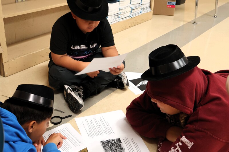 Three students are sitting on the floor discussing the book and their findings.