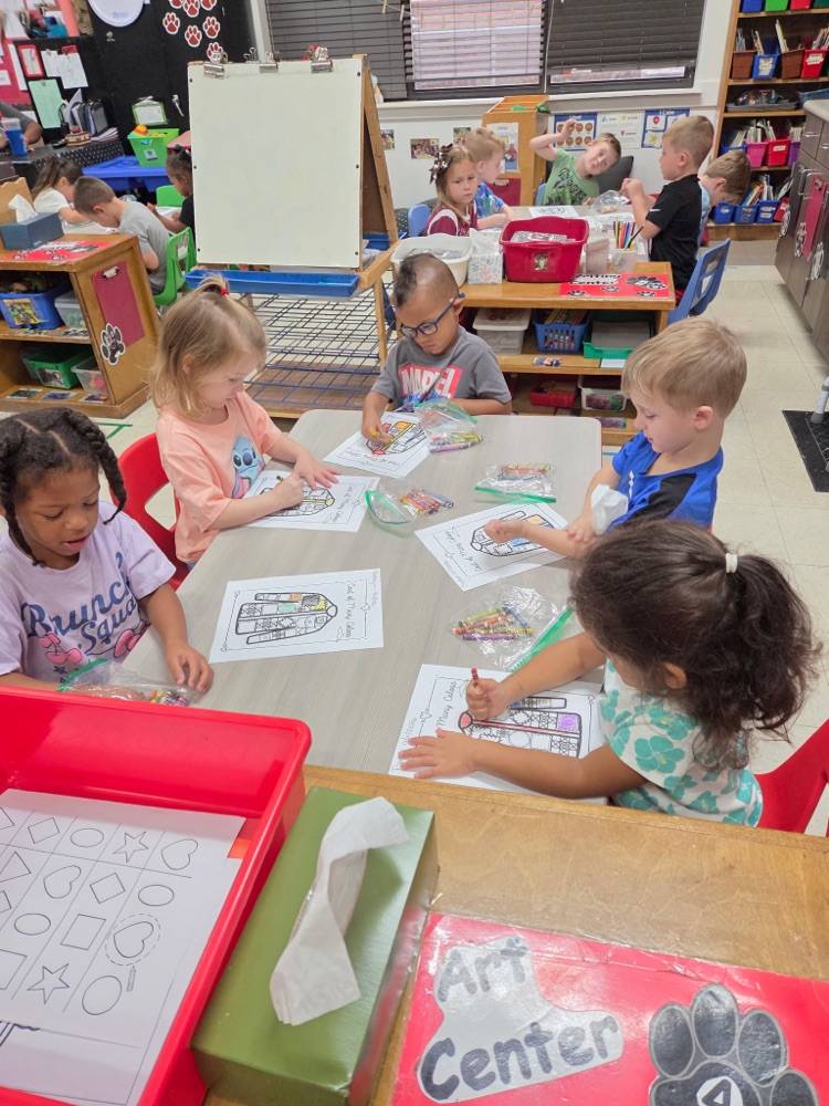 Pre-K students coloring coat of many colors