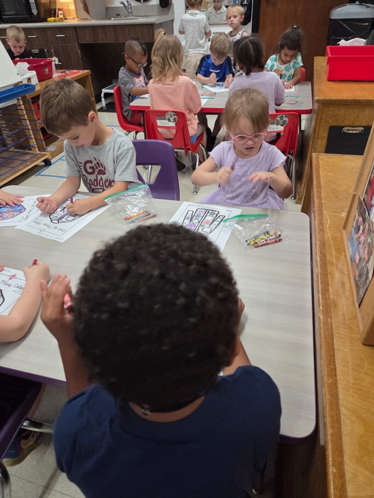 Pre-K students coloring coat of many colors