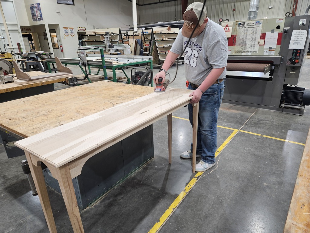 Caleb Dosch sanding on his table.