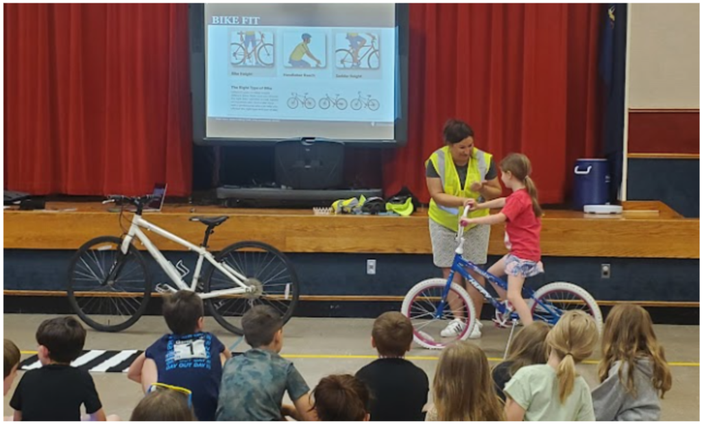 PennDot worker helping girl ride bike.