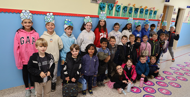 Students smiling in hallway wearing paper hats.