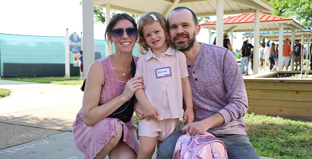 Student smiling with parents.