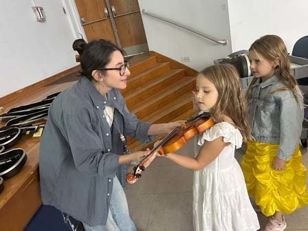 Teacher showing student how to hold violin.