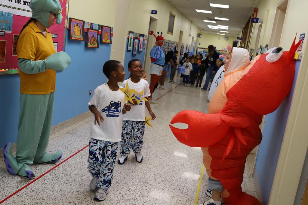 students in hall looking at people dressed in costumes