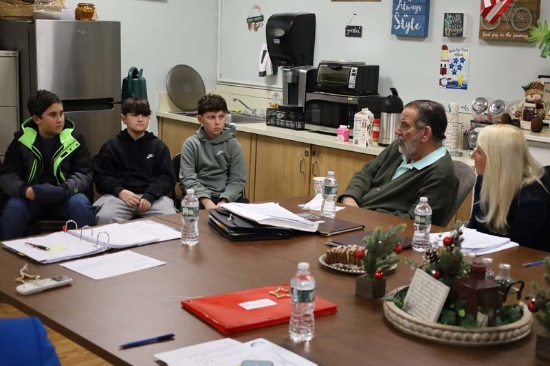 Students sitting with older man at desk.