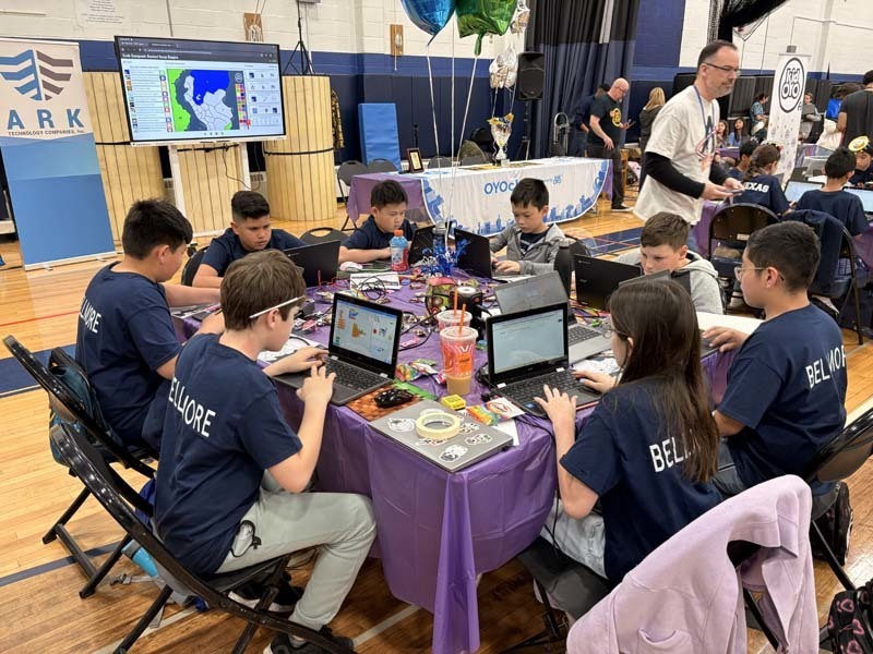 Students sitting at table with laptops.