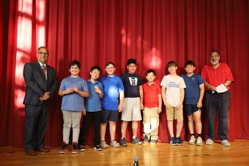 Students on stage in front of red curtain.